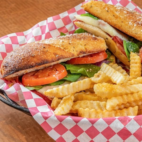 Two Armando's Grill & Pizzeria subs with tomatoes, lettuce, and cheese, served with crinkle-cut fries.
